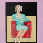 Marilyn Monroe sitzt im roten Sessel und trägt ein grünes Kleid und rote Schuhe
